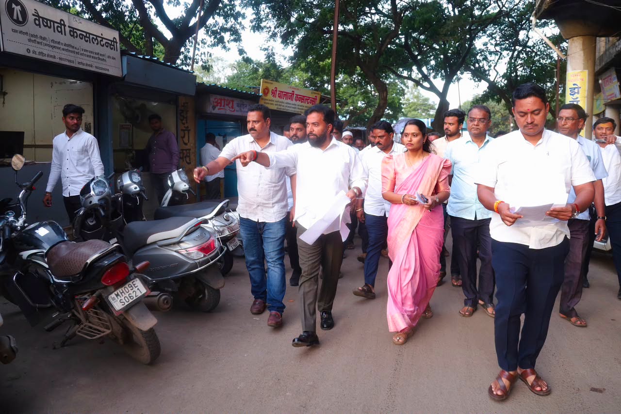 Rahul Awade walking a market street in Ichalkaranji with municipal officials during a civic inspection, papers in hand.