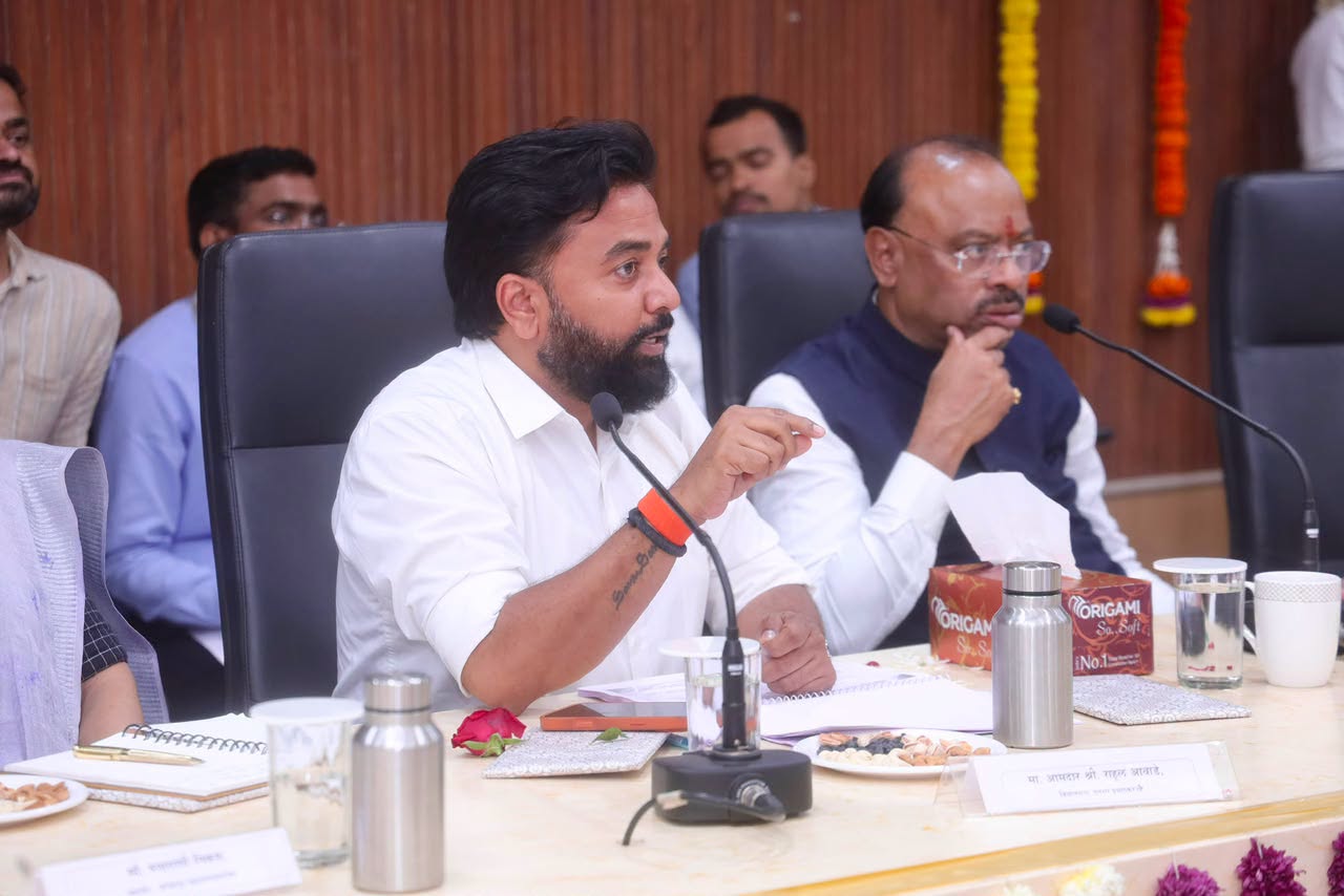 Rahul Awade speaking at an official review meeting in Ichalkaranji, seated at a conference table with departmental officials and a nameplate reading Aamdar Shri Rahul Awade.