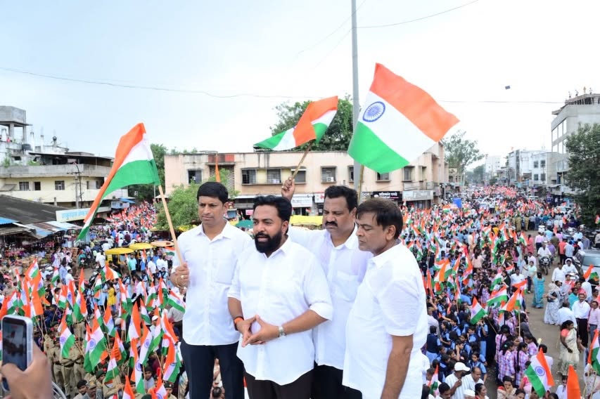 Rahul Awade waving the National Flag above a large public tiranga rally on an Ichalkaranji street.