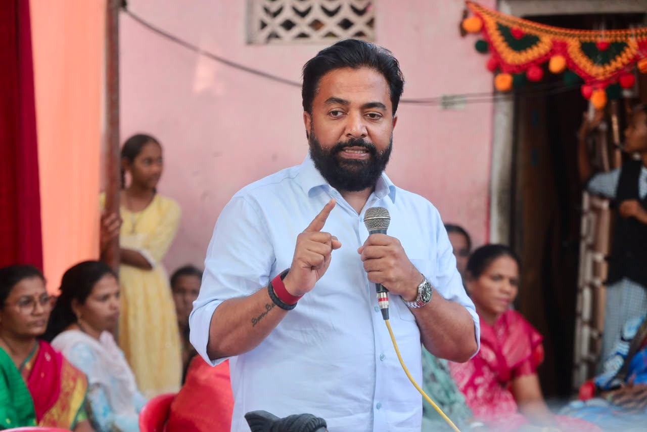 Rahul Awade speaking at a neighbourhood gathering in Ichalkaranji, with residents seated around him.